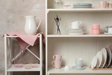 White shelving unit with set of dishware near wall