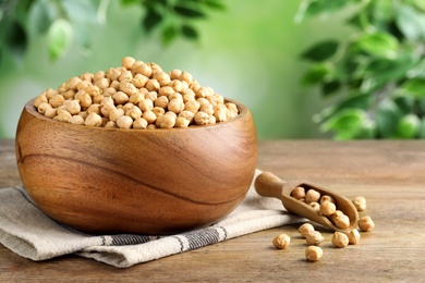 Photo of Raw chickpeas in bowl on wooden table