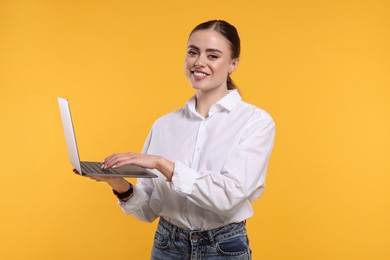Photo of Happy woman with laptop on orange background