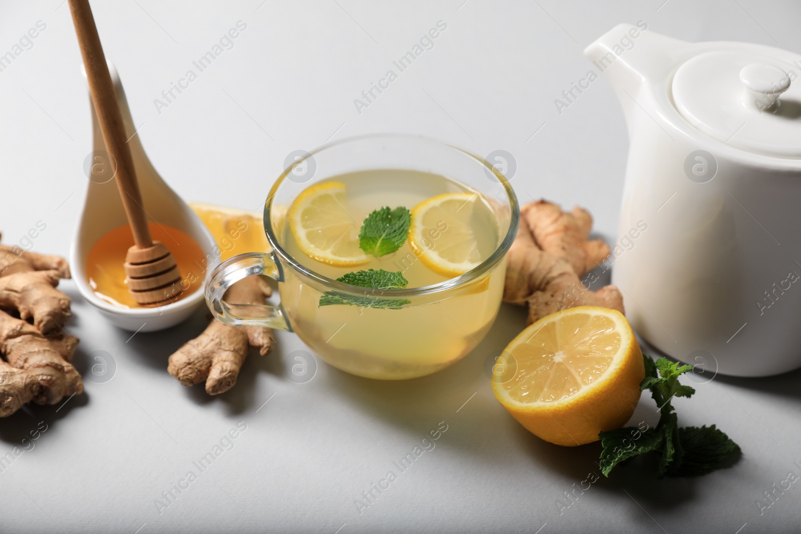 Photo of Delicious ginger tea and ingredients on light grey background