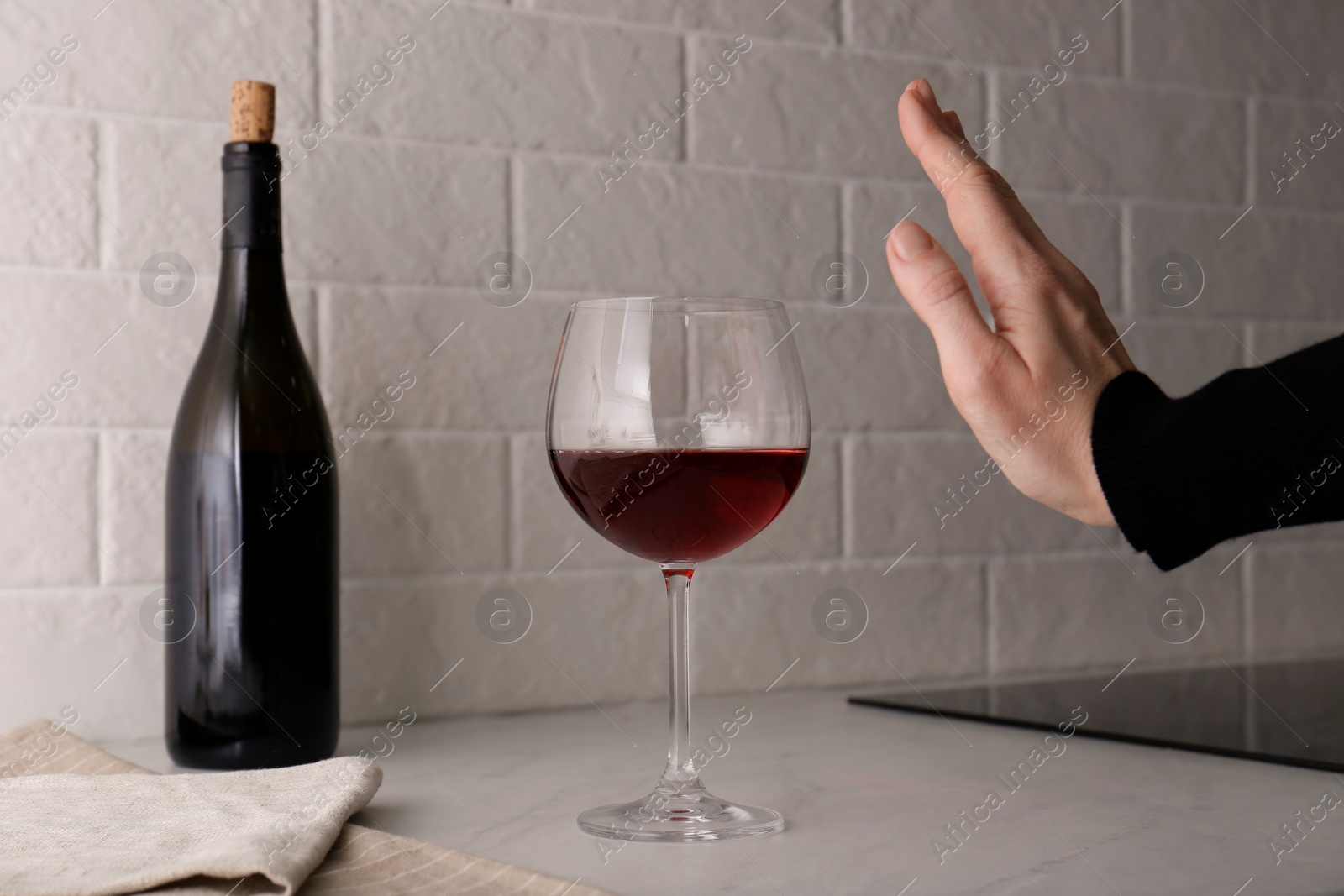 Photo of Woman refusing to drink red wine at home, closeup. Alcohol addiction treatment