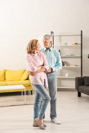 Photo of Happy senior couple dancing together in living room