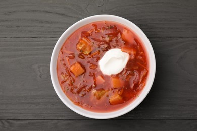 Tasty borscht with sour cream on grey wooden table, top view