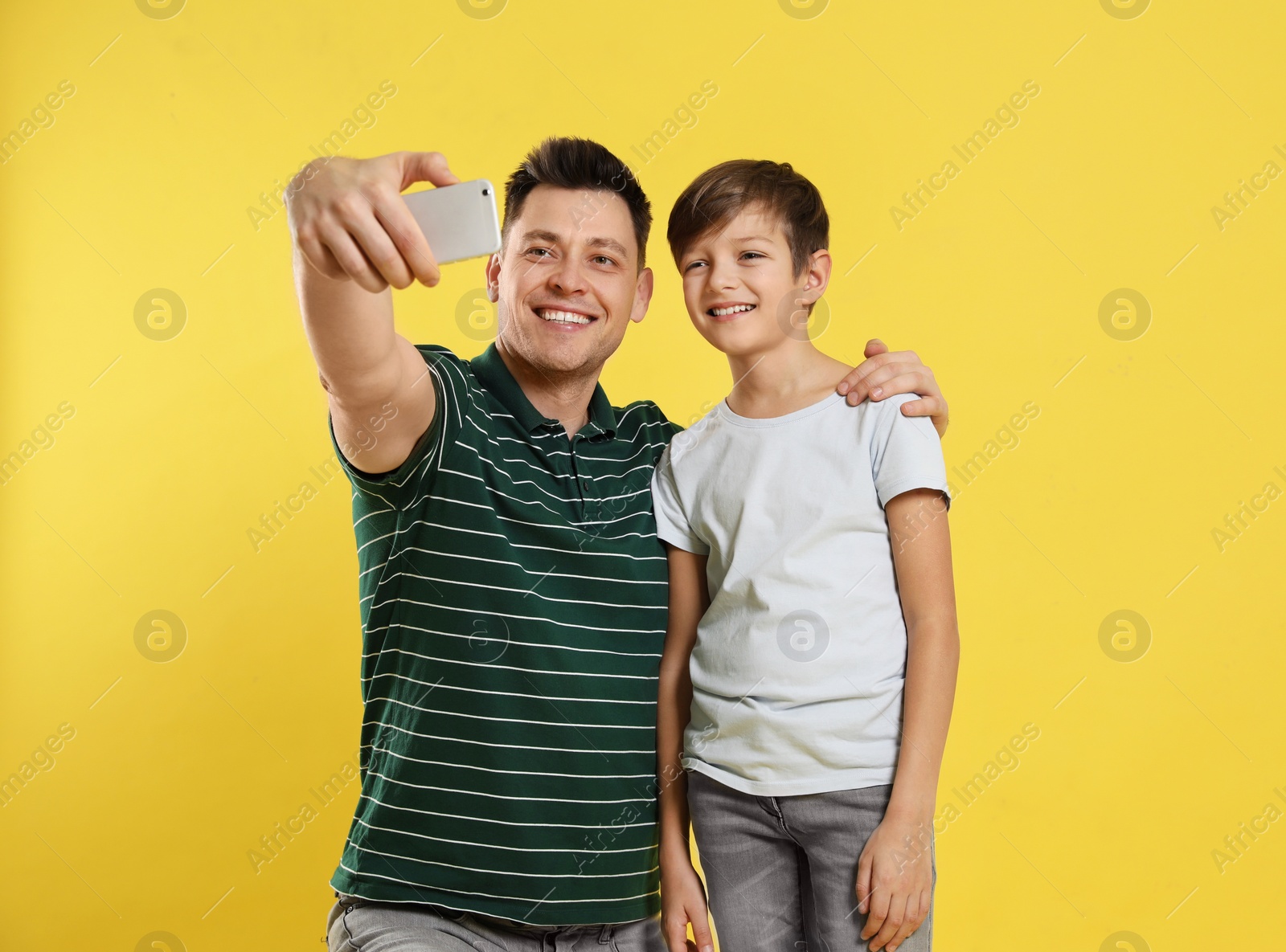 Photo of Dad and his son taking selfie on color background