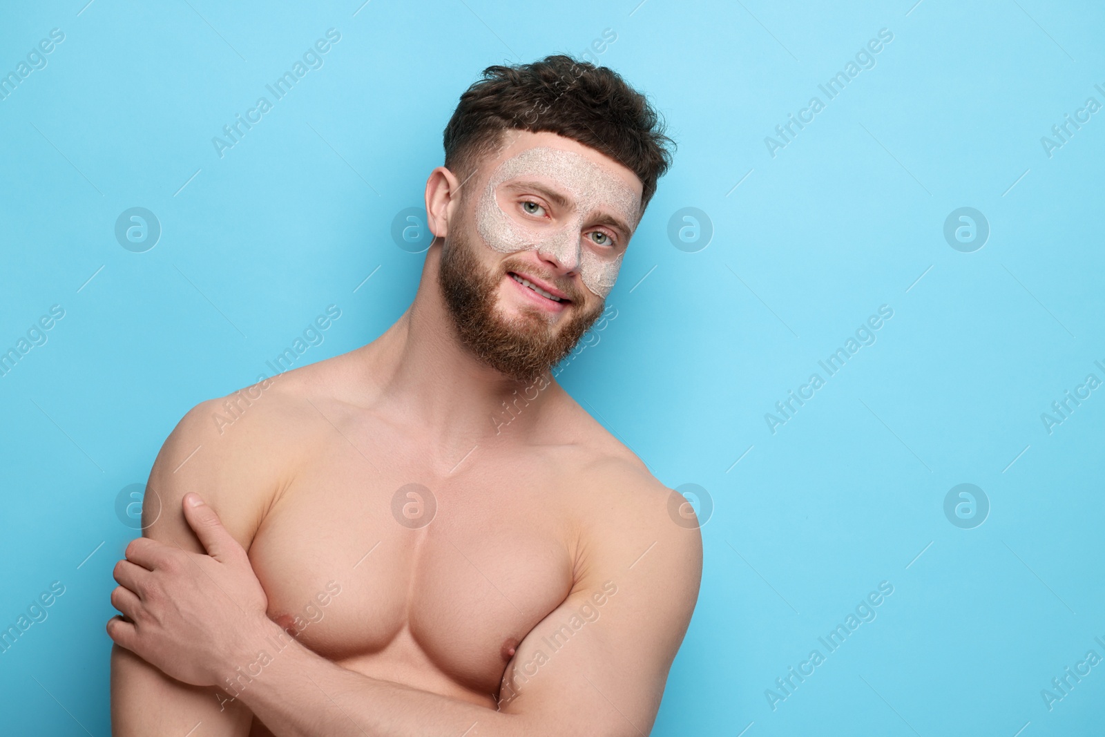 Photo of Handsome man with facial mask on his face against light blue background, space for text