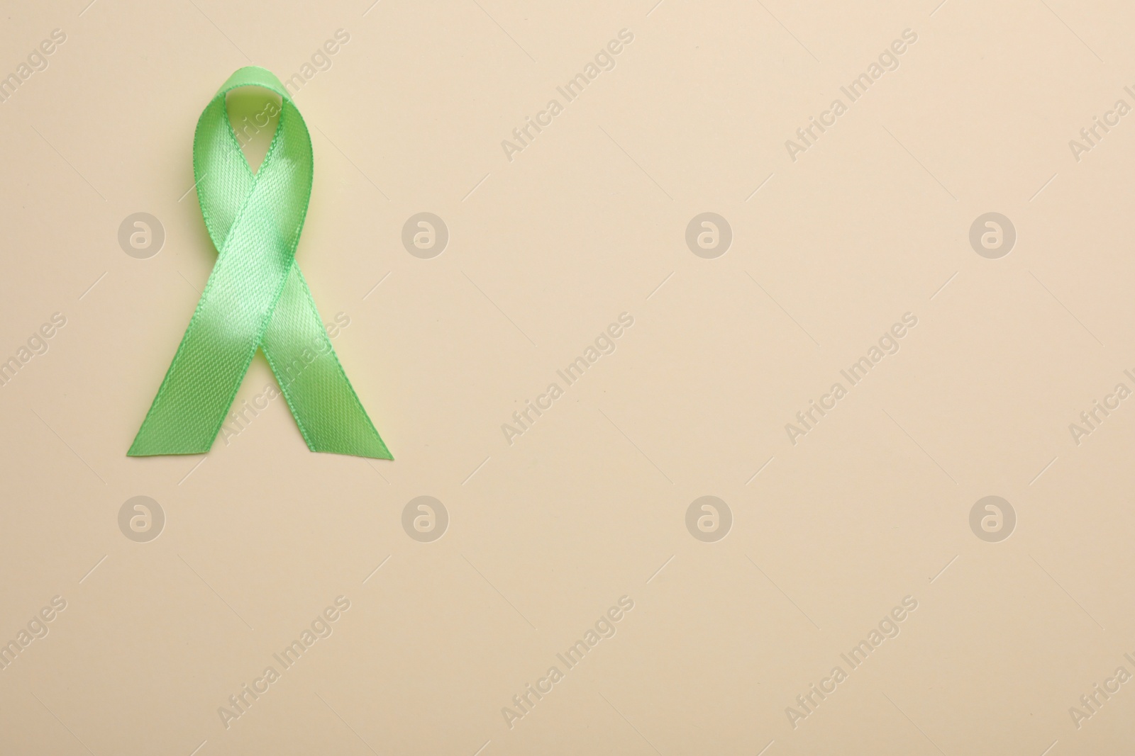 Photo of World Mental Health Day. Green ribbon on color background, top view with space for text