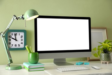 Stylish workplace with modern computer near light green wall indoors. Space for text