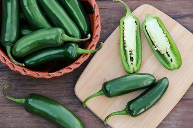 Photo of Whole and cut jalapeno peppers on wooden table, flat lay