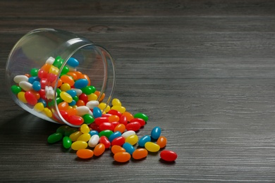 Jar with jelly beans on wooden background. Space for text