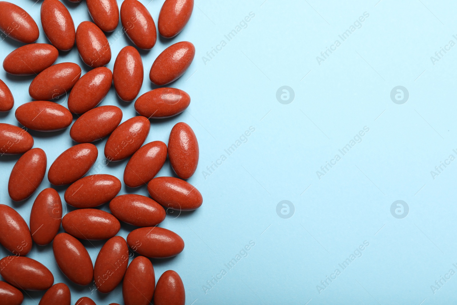 Photo of Brown pills and space for text on light blue background, flat lay. Anemia concept