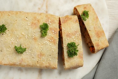 Photo of Cut tasty strudel with chicken and vegetables on light wooden table, top view
