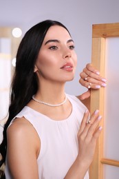 Photo of Young woman wearing elegant pearl jewelry indoors