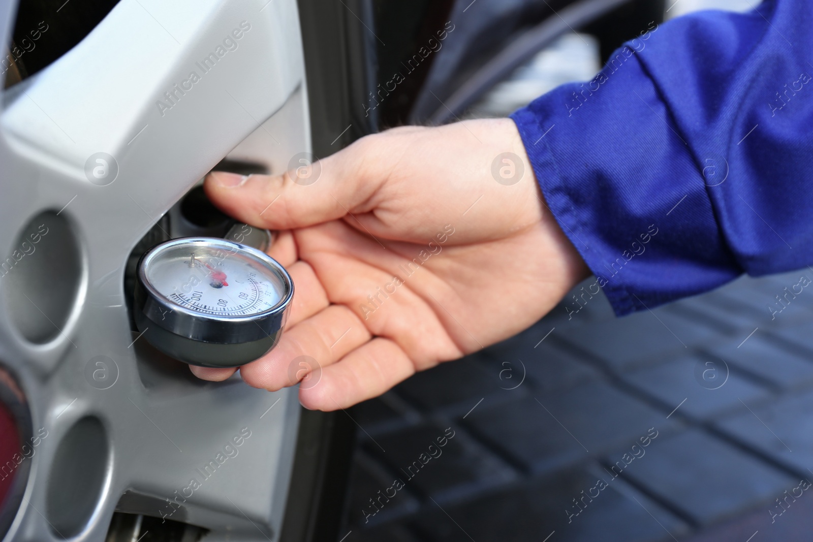 Photo of Mechanic checking tire air pressure at car service, closeup