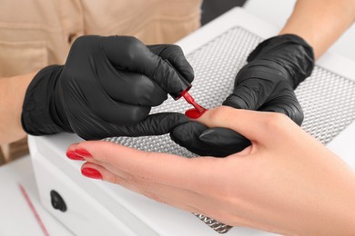 Photo of Professional manicurist working with client at table, closeup