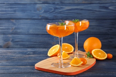 Photo of Dessert glasses of orange jelly served on blue wooden table. Space for text