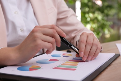 Photo of Businesswoman working with charts and graphs at table in office, closeup. Investment analysis