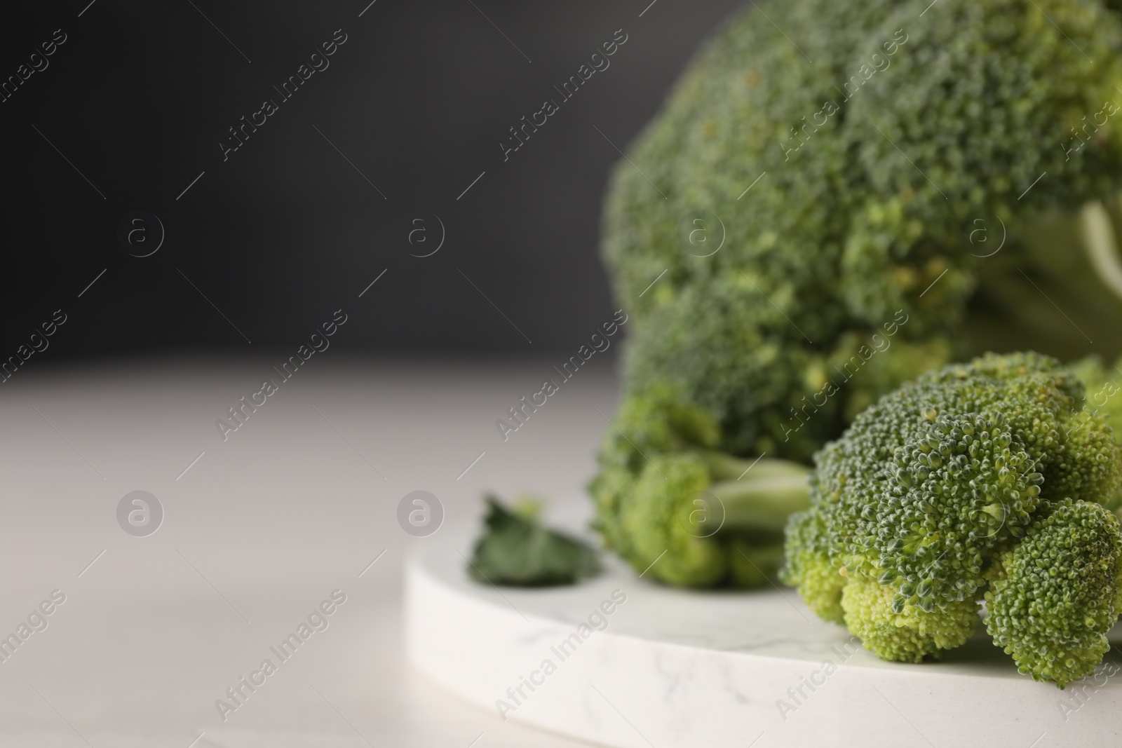 Photo of Fresh raw broccoli on white table, closeup. Space for text