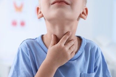 Photo of Endocrine system. Little boy doing thyroid self examination indoors, closeup
