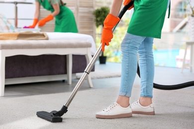 Woman removing dirt from carpet with vacuum cleaner in bedroom