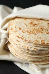 Photo of Stack of tasty homemade tortillas on black table