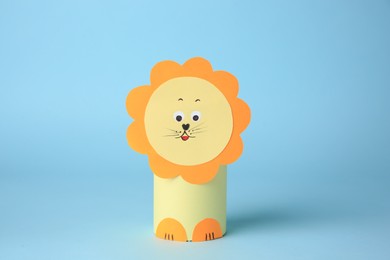 Photo of Toy lion made from toilet paper hub on light blue background. Children's handmade ideas