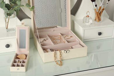 Photo of Jewelry boxes with stylish golden bijouterie on white dressing table