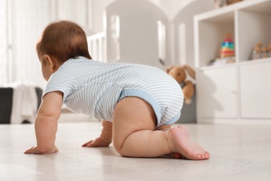 Photo of Cute baby crawling on floor at home, back view