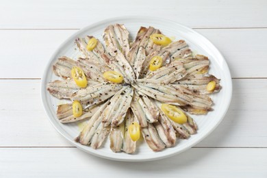 Photo of Tasty pickled anchovies with spices on white wooden table, closeup