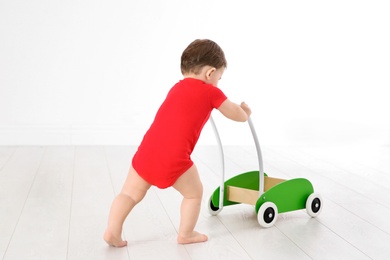 Cute baby playing with toy walker, indoors