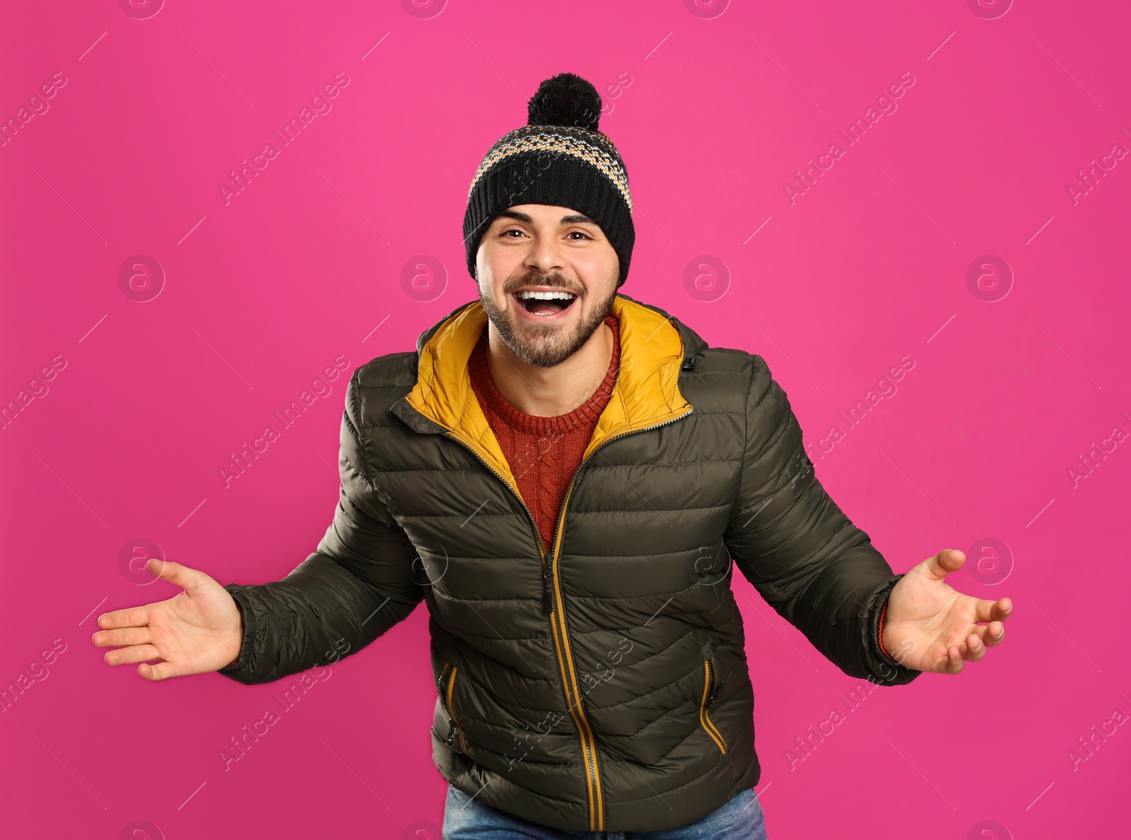 Photo of Happy young man in warm clothes on pink background. Winter vacation