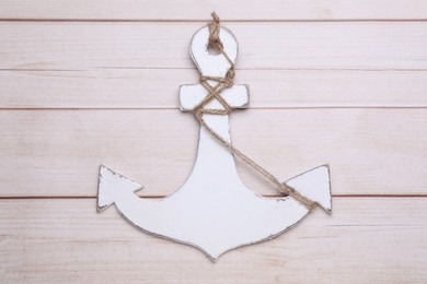 Photo of Anchor with hemp rope on wooden table, top view