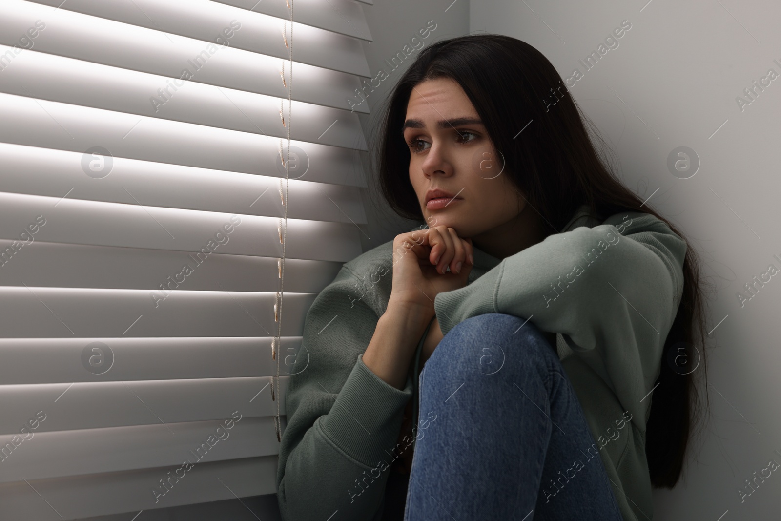 Photo of Sadness. Unhappy woman near window at home