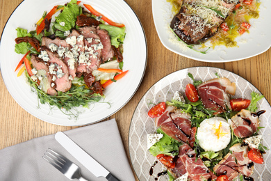 Photo of Flat lay composition with delicious prosciutto salad on wooden table