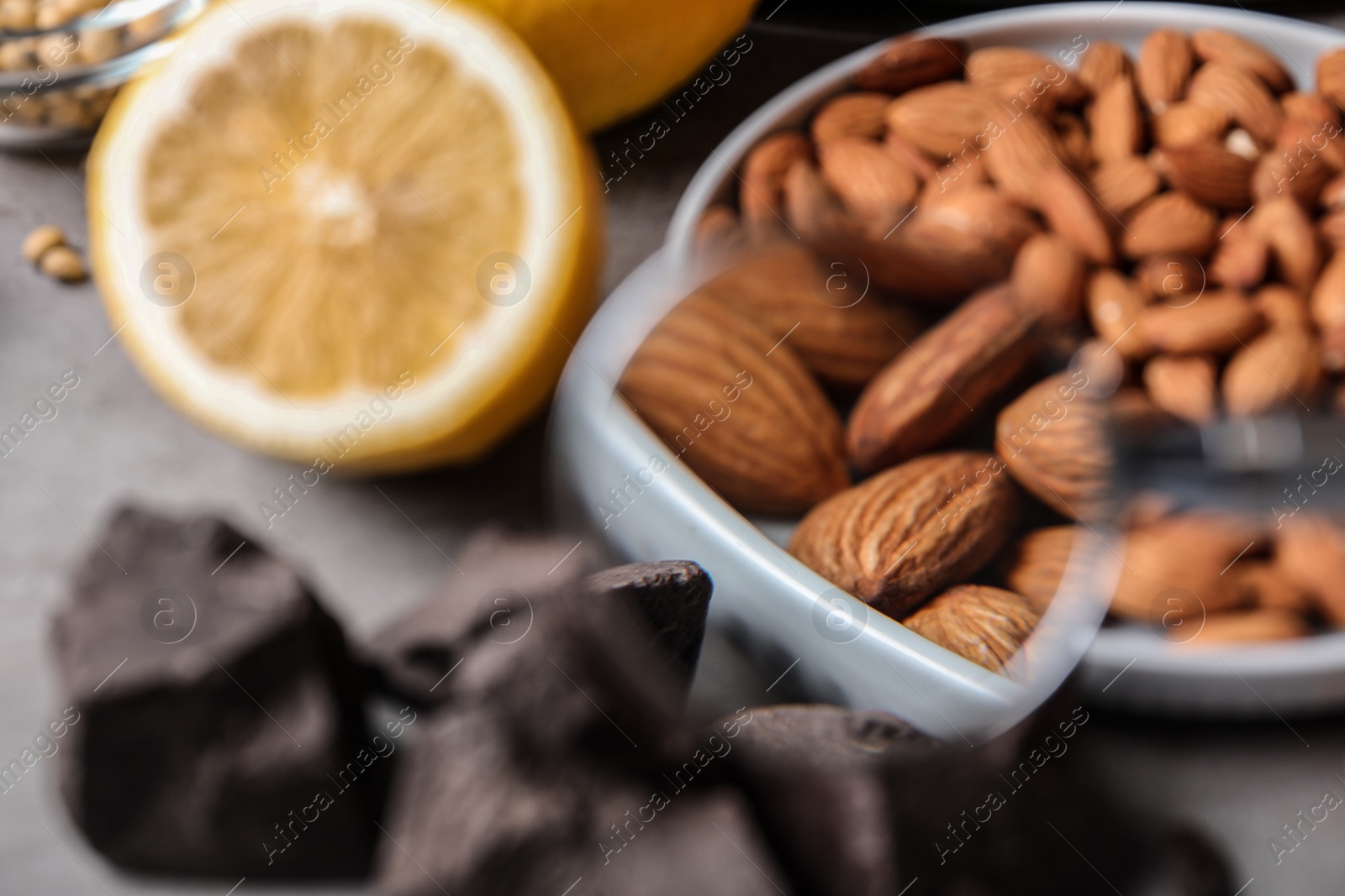 Photo of Different products with magnifier focused on almonds, closeup. Food allergy concept