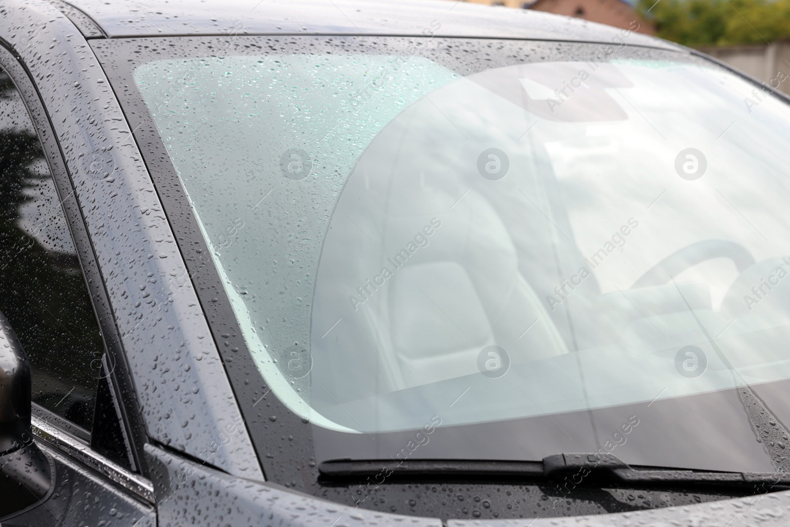 Photo of Car wiper cleaning water drops from windshield glass, closeup