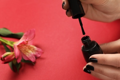 Photo of Woman opening nail polish bottle on color background, closeup. Space for text