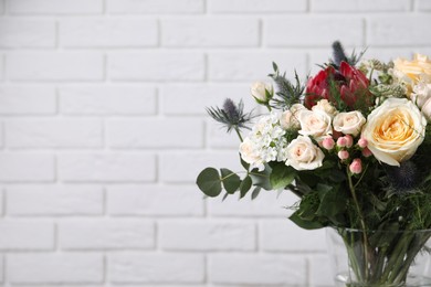 Photo of Beautiful bouquet with roses against white brick wall, closeup. Space for text