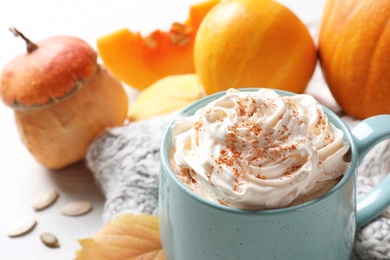 Cup with pumpkin spice latte and  autumn decor on light table