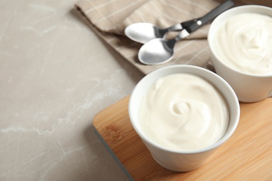 Bowls with creamy yogurt served on table. Space for text