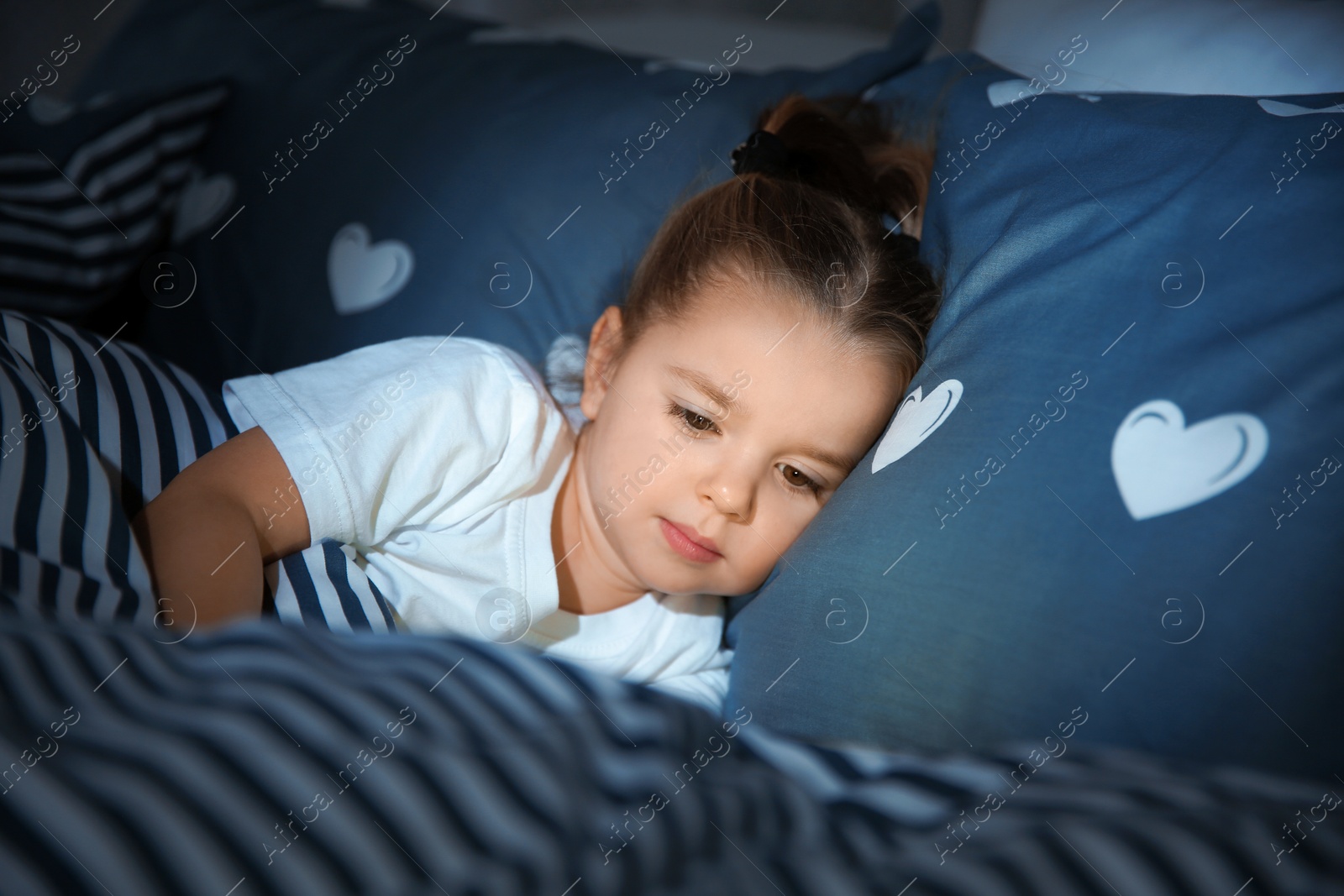 Photo of Beautiful little girl with gadget in bed at night. Bedtime schedule
