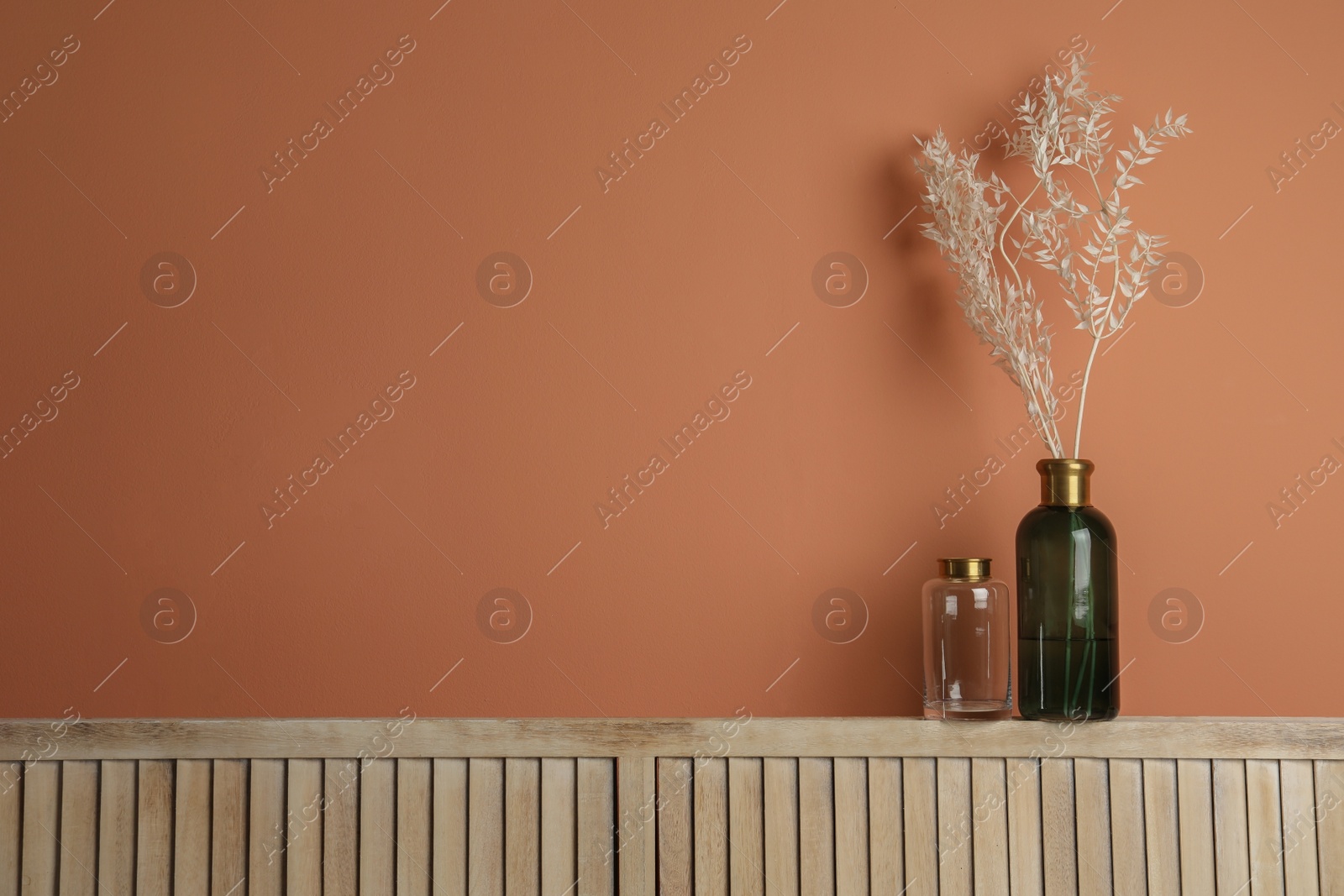 Photo of Decorative vases on wooden shelf near wall indoors