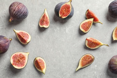 Photo of Flat lay composition with whole and cut purple figs and space for text on gray background