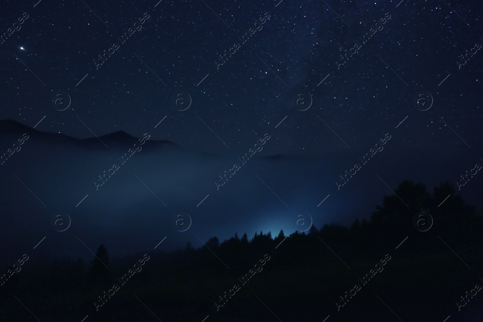 Photo of Picturesque view of night sky with beautiful stars over foggy hill