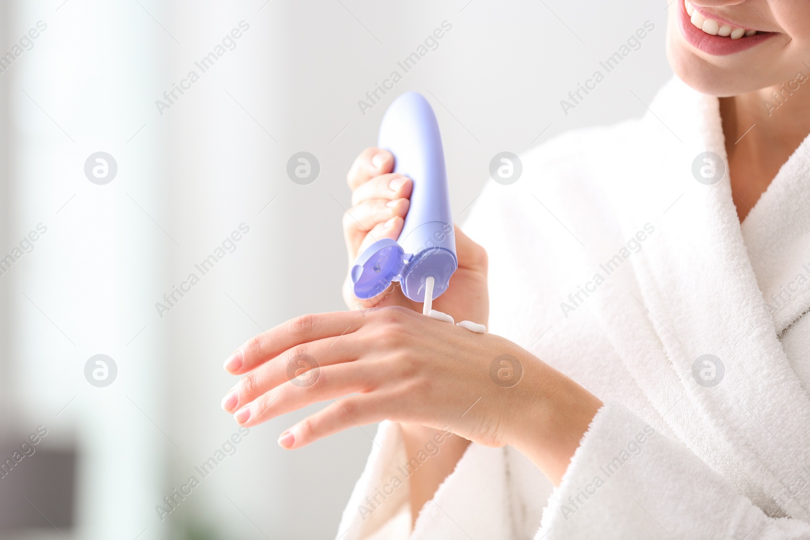 Photo of Young woman applying hand cream at home, closeup