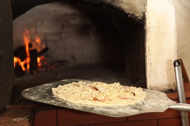 Putting pizza into oven in restaurant kitchen