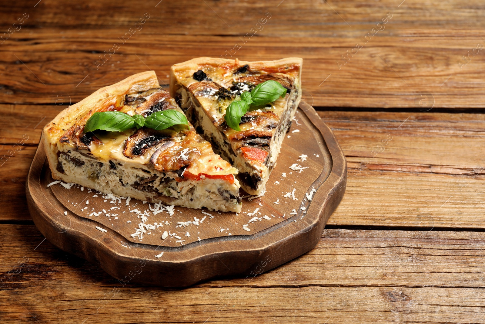 Photo of Pieces of delicious quiche with mushrooms on wooden table