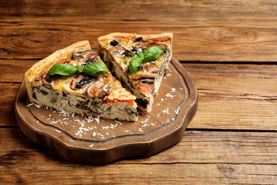 Photo of Pieces of delicious quiche with mushrooms on wooden table
