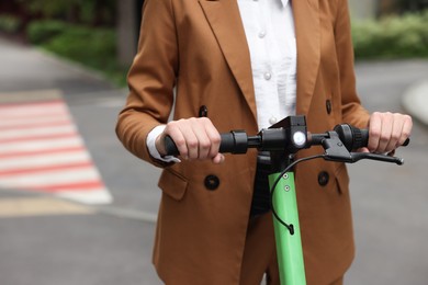 Photo of Businesswoman riding electric kick scooter on city street, closeup. Space for text