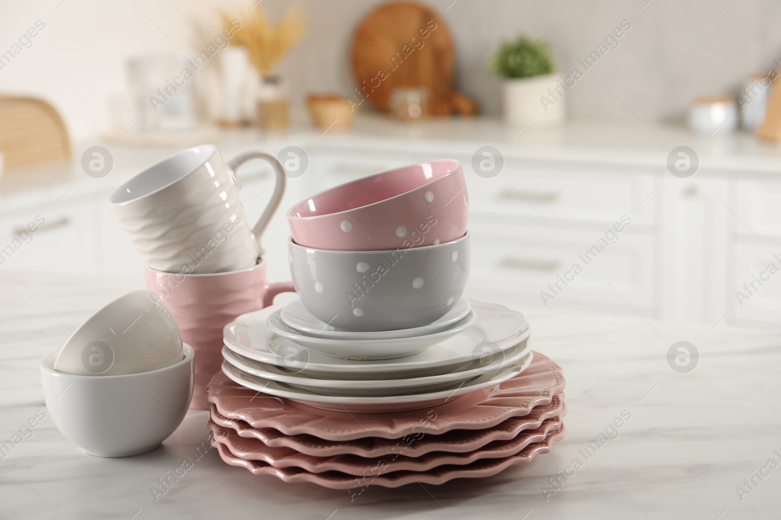 Photo of Many different clean dishware and cups on white marble table in kitchen