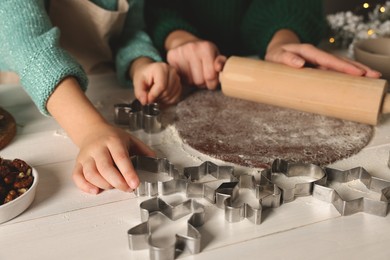 Photo of Mother and child making Christmas cookies at white wooden table together, closeup